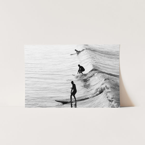 a black and white photo of two people surfing