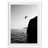 a black and white photo of a person jumping off a cliff into the ocean