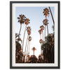 a framed photograph of palm trees against a blue sky