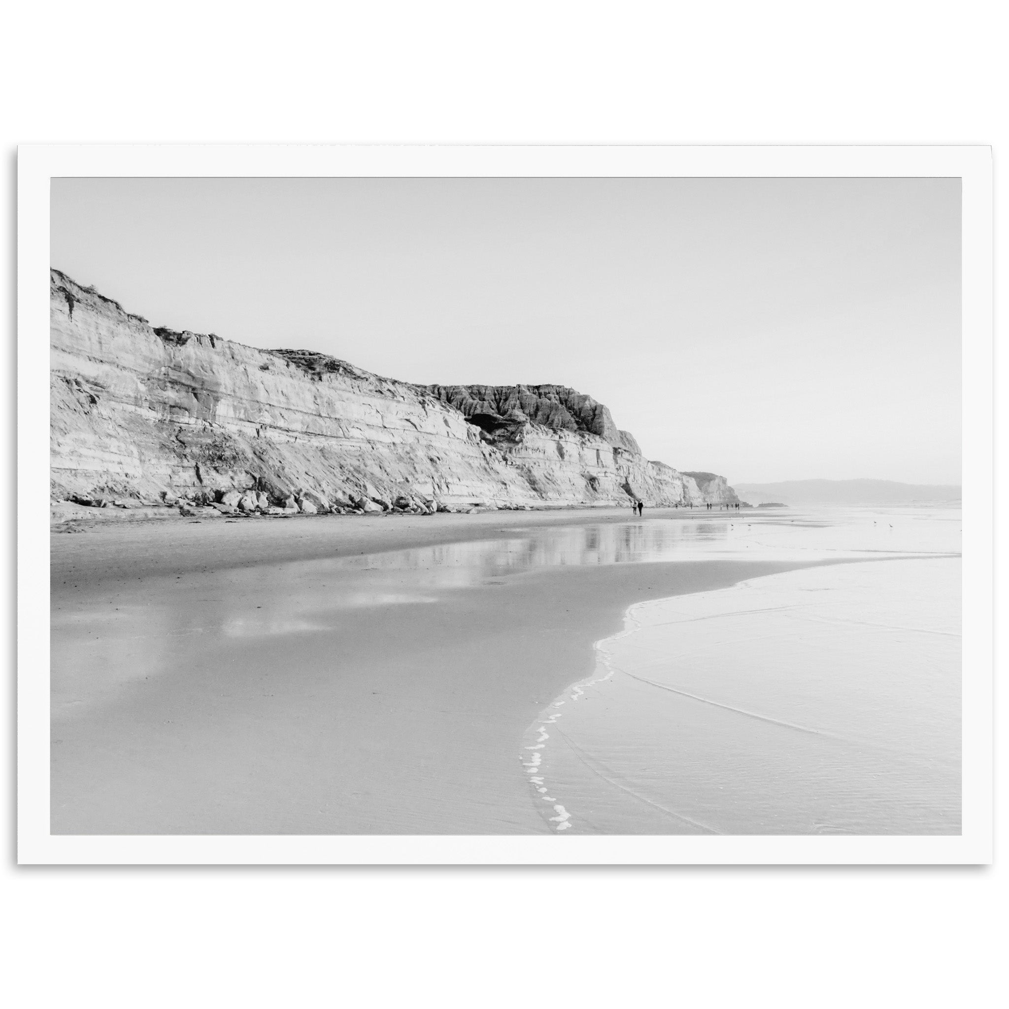 a black and white photo of a person walking on a beach