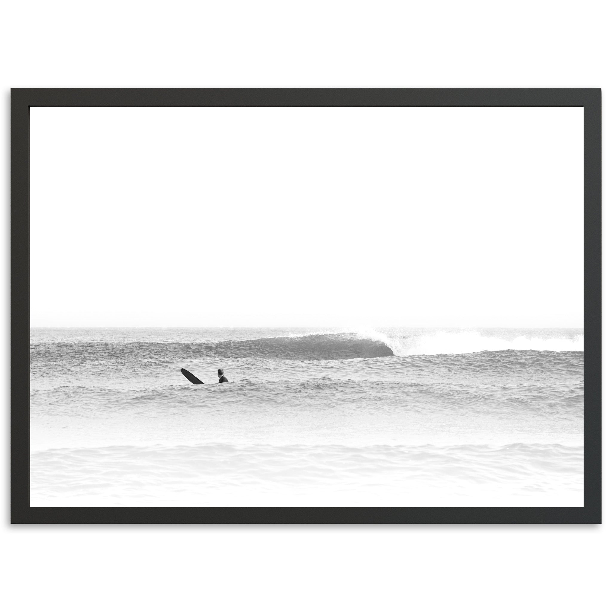 a black and white photo of two surfers in the ocean