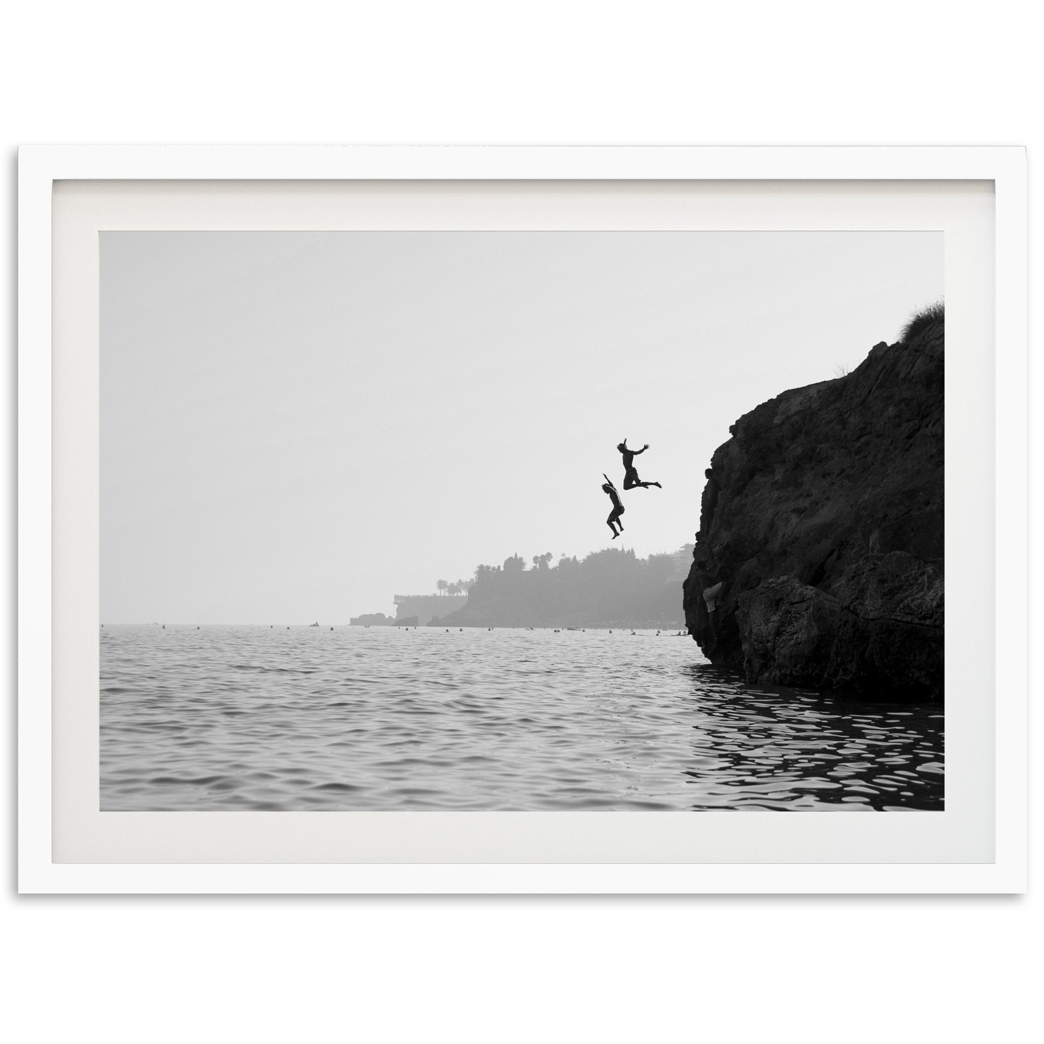 a black and white photo of a person jumping off a cliff into the ocean