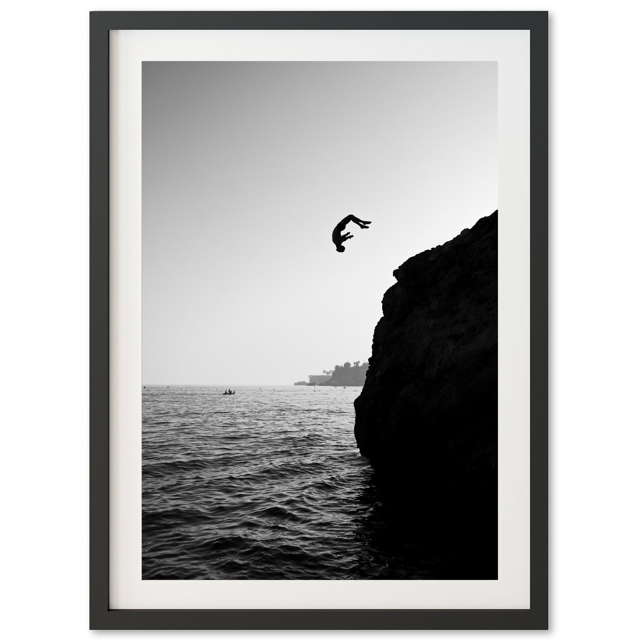 a black and white photo of a person jumping off a cliff into the ocean