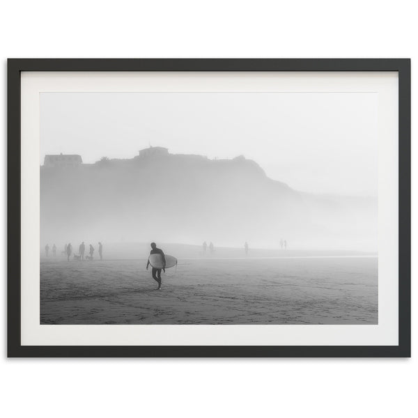 a black and white photo of a person carrying a surfboard