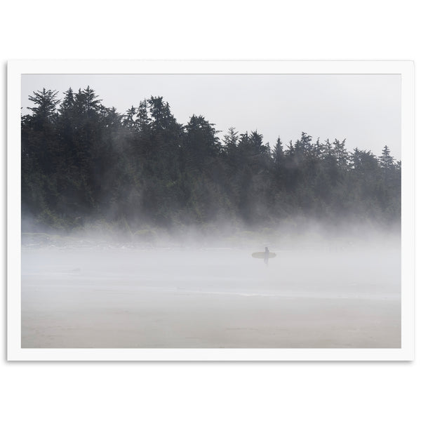 a person standing on a beach with a surfboard in the fog