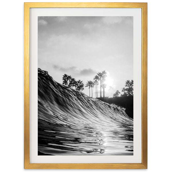 a black and white photo of a wave with palm trees in the background