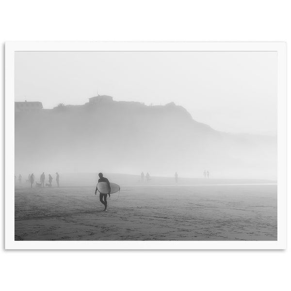 a black and white photo of a person carrying a surfboard