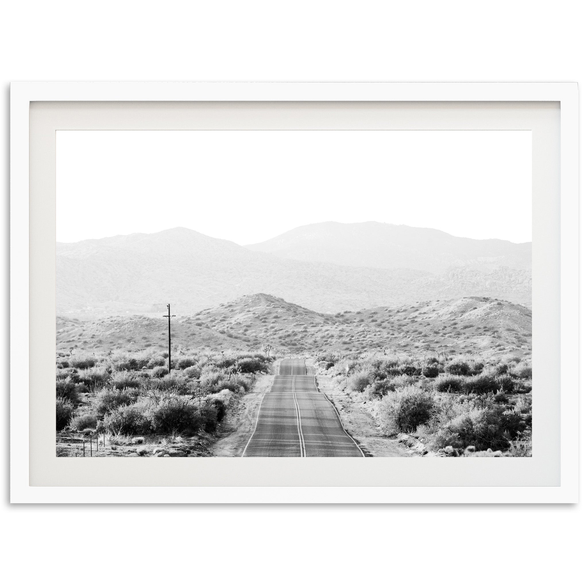 a black and white photo of a road in the desert