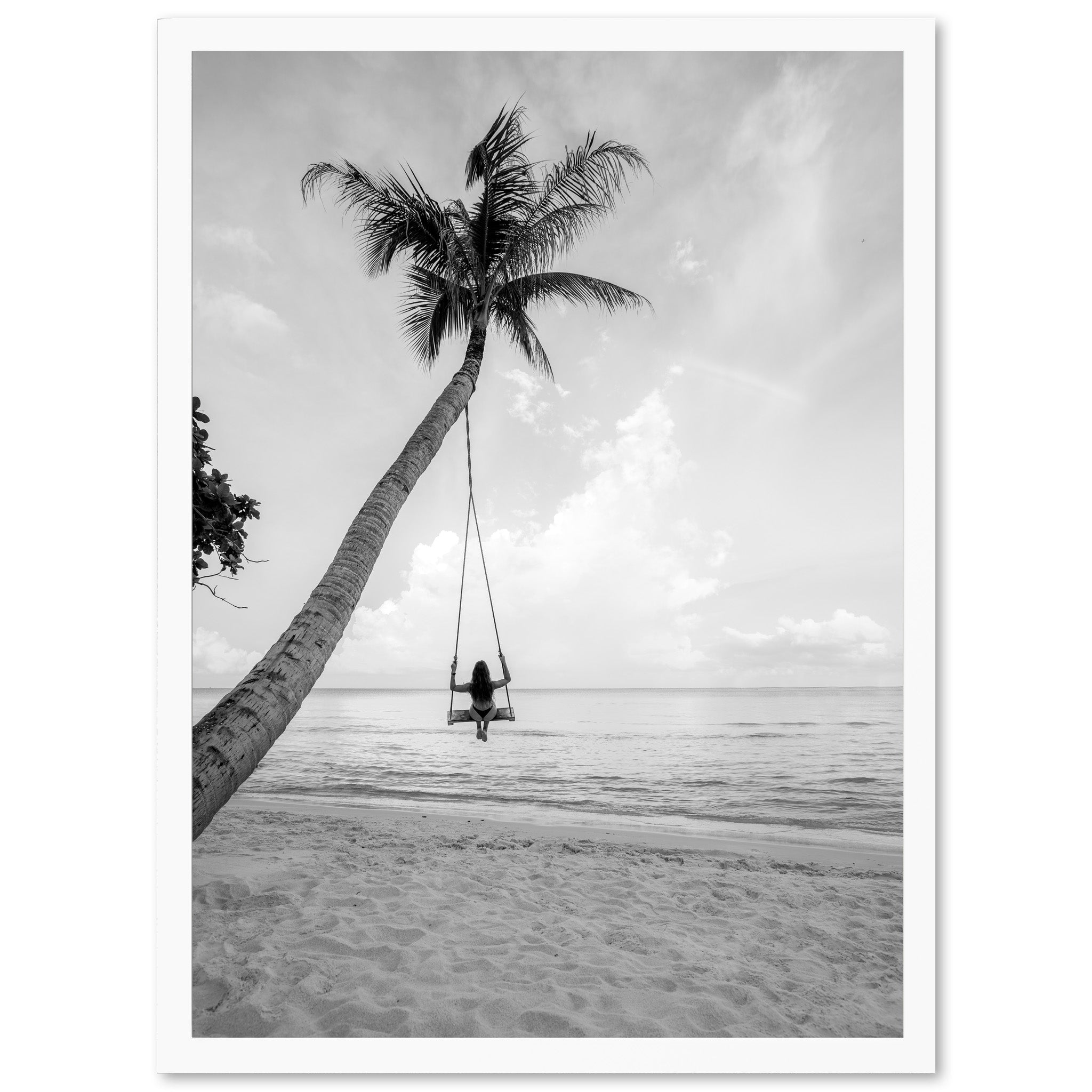 a black and white photo of a person swinging on a palm tree