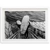 a black and white photo of a person carrying a surfboard