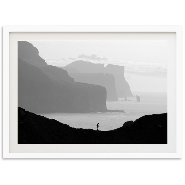 a black and white photo of a person standing on a cliff