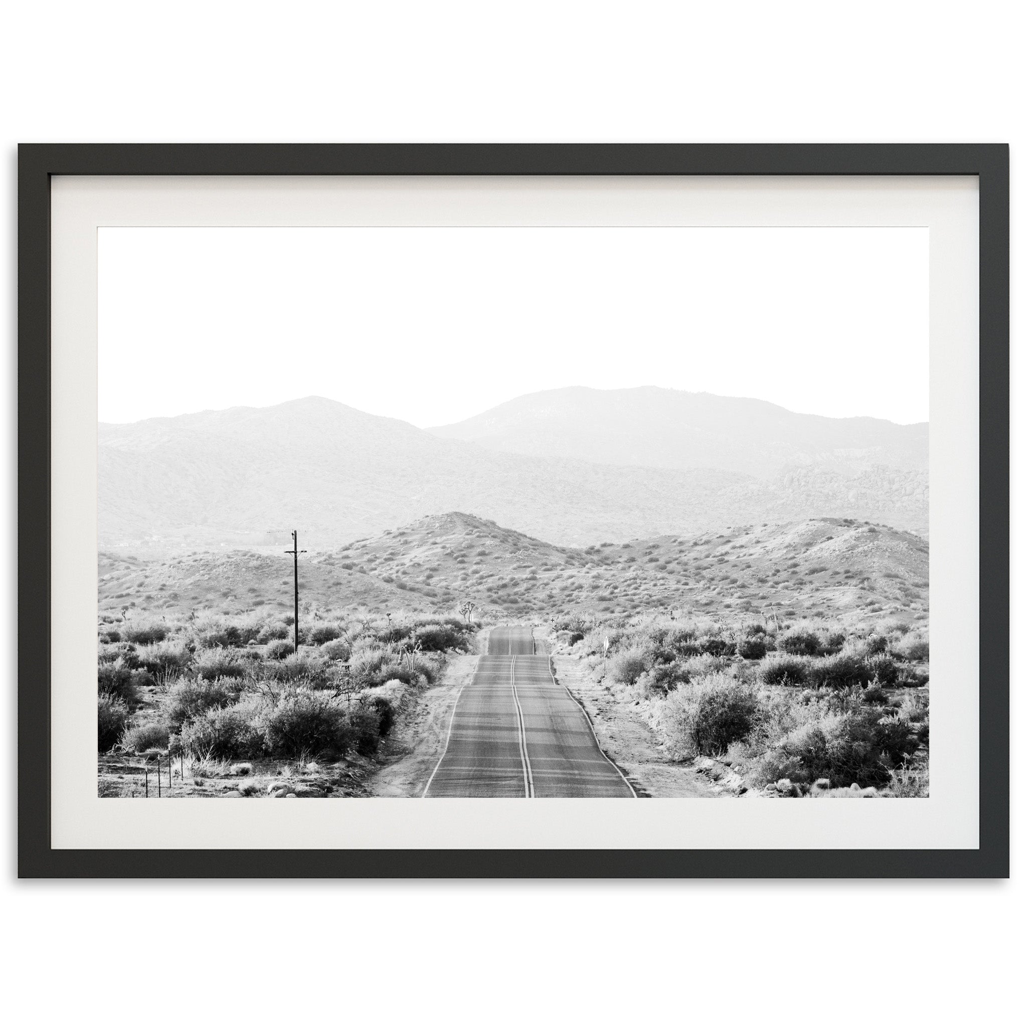 a black and white photo of a road in the desert