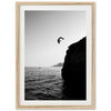 a black and white photo of a person jumping off a cliff into the ocean