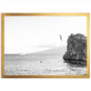 a black and white photo of a person jumping off a cliff into the ocean