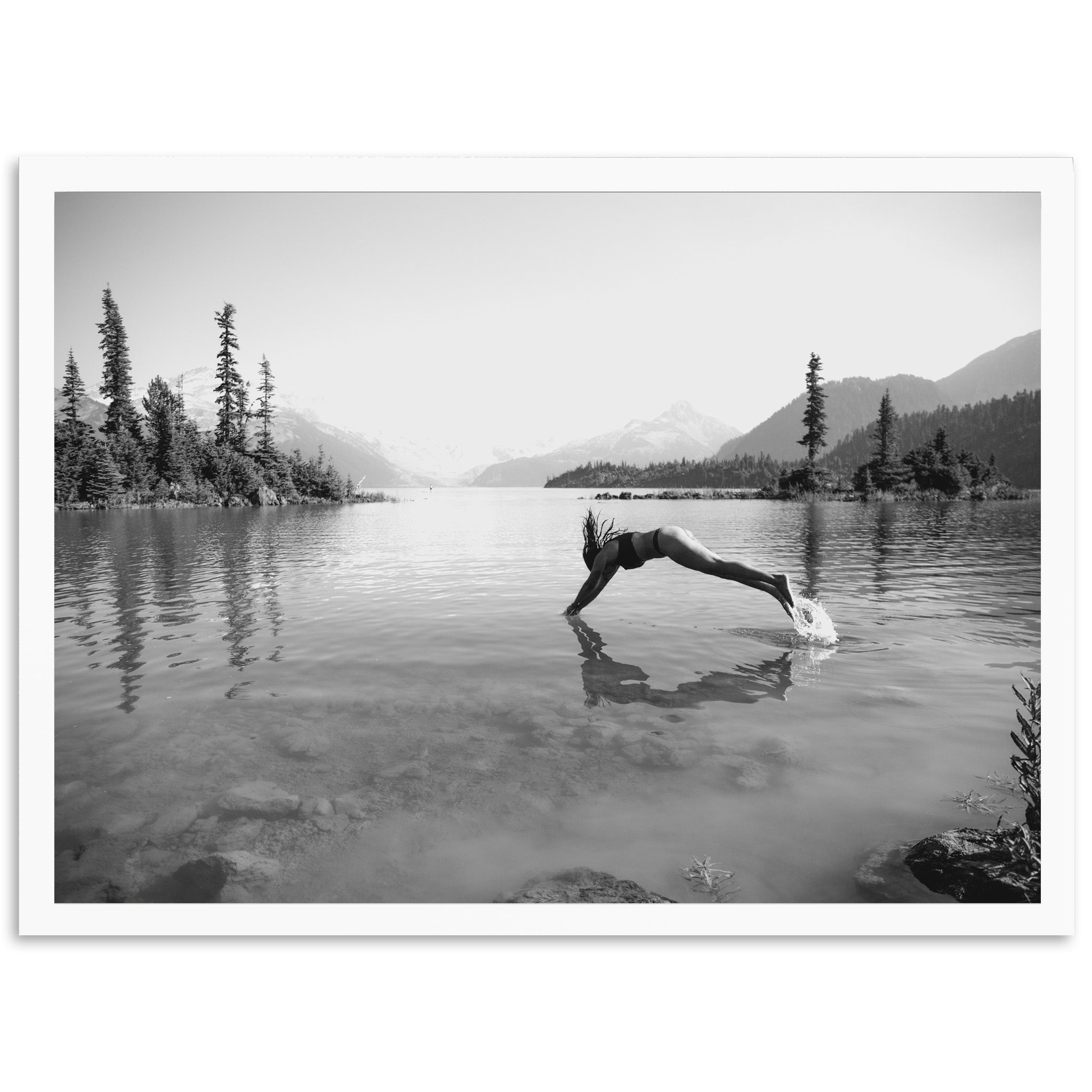 a black and white photo of a person diving into a lake