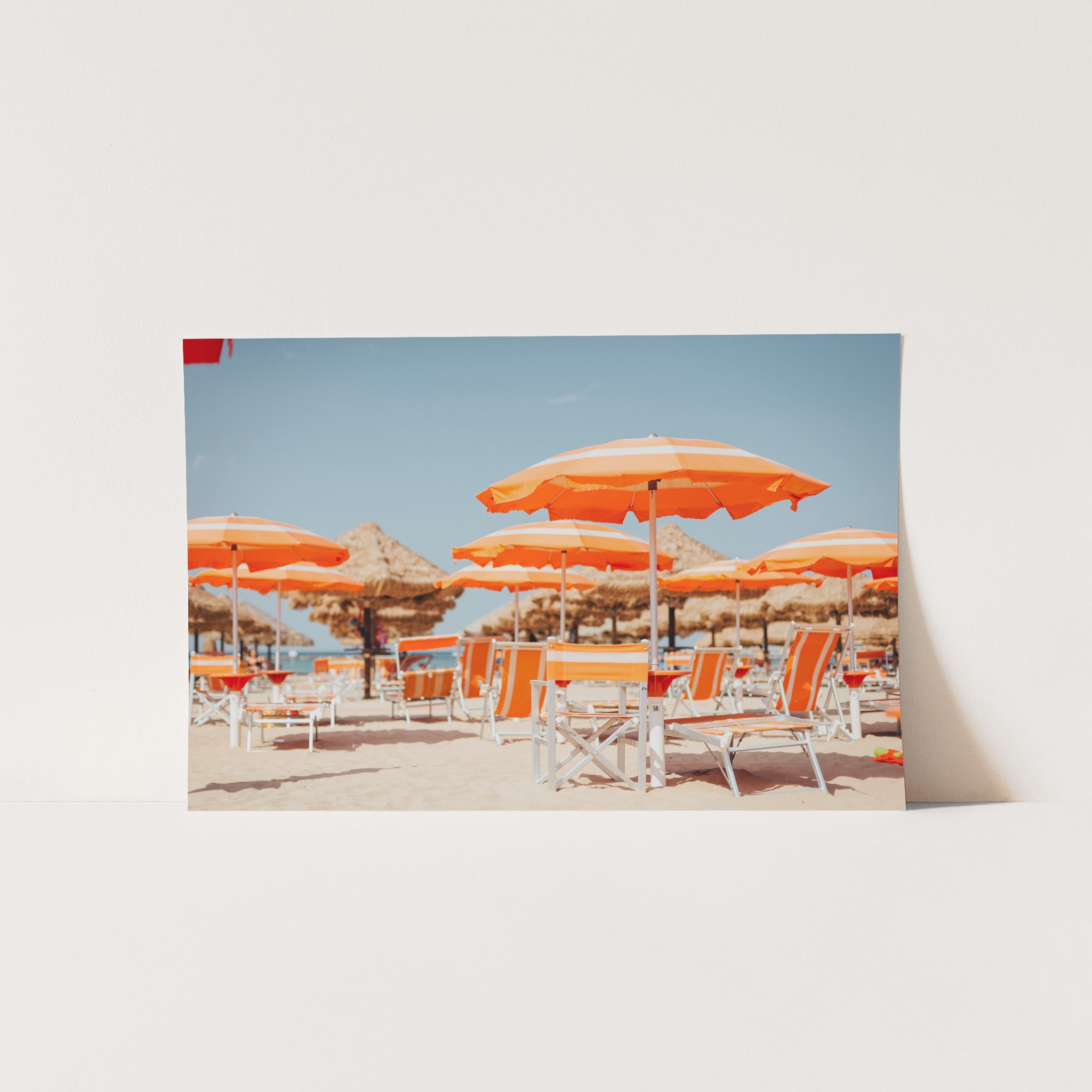 a group of orange umbrellas sitting on top of a sandy beach