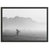 a black and white photo of a person carrying a surfboard