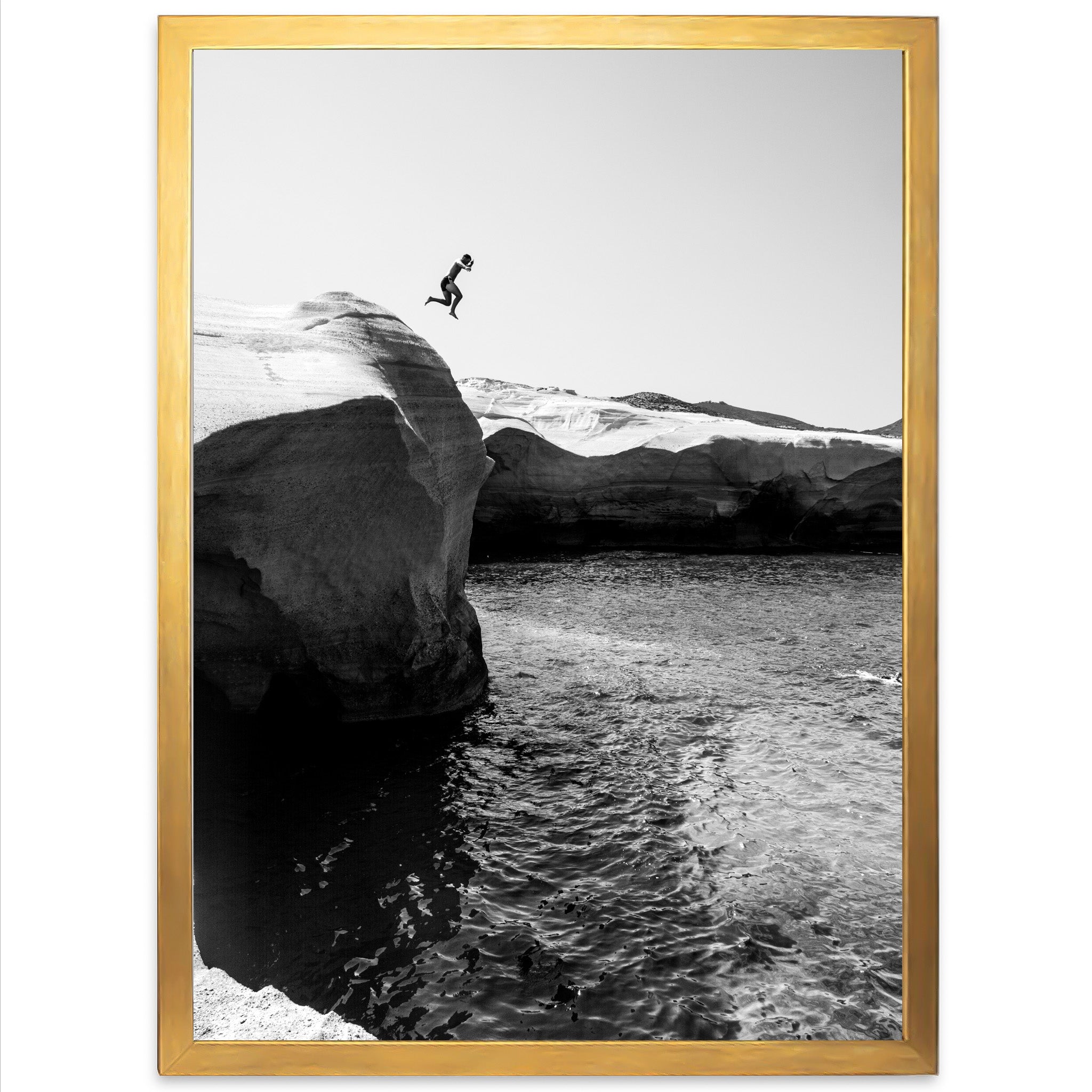 a black and white photo of a person jumping off a cliff into the water