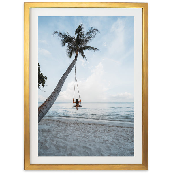 a person sitting on a swing between two palm trees