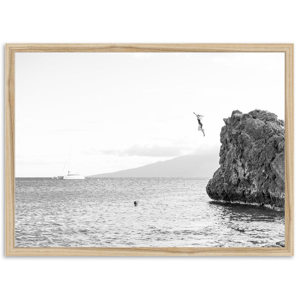 a black and white photo of a person jumping off a cliff into the ocean