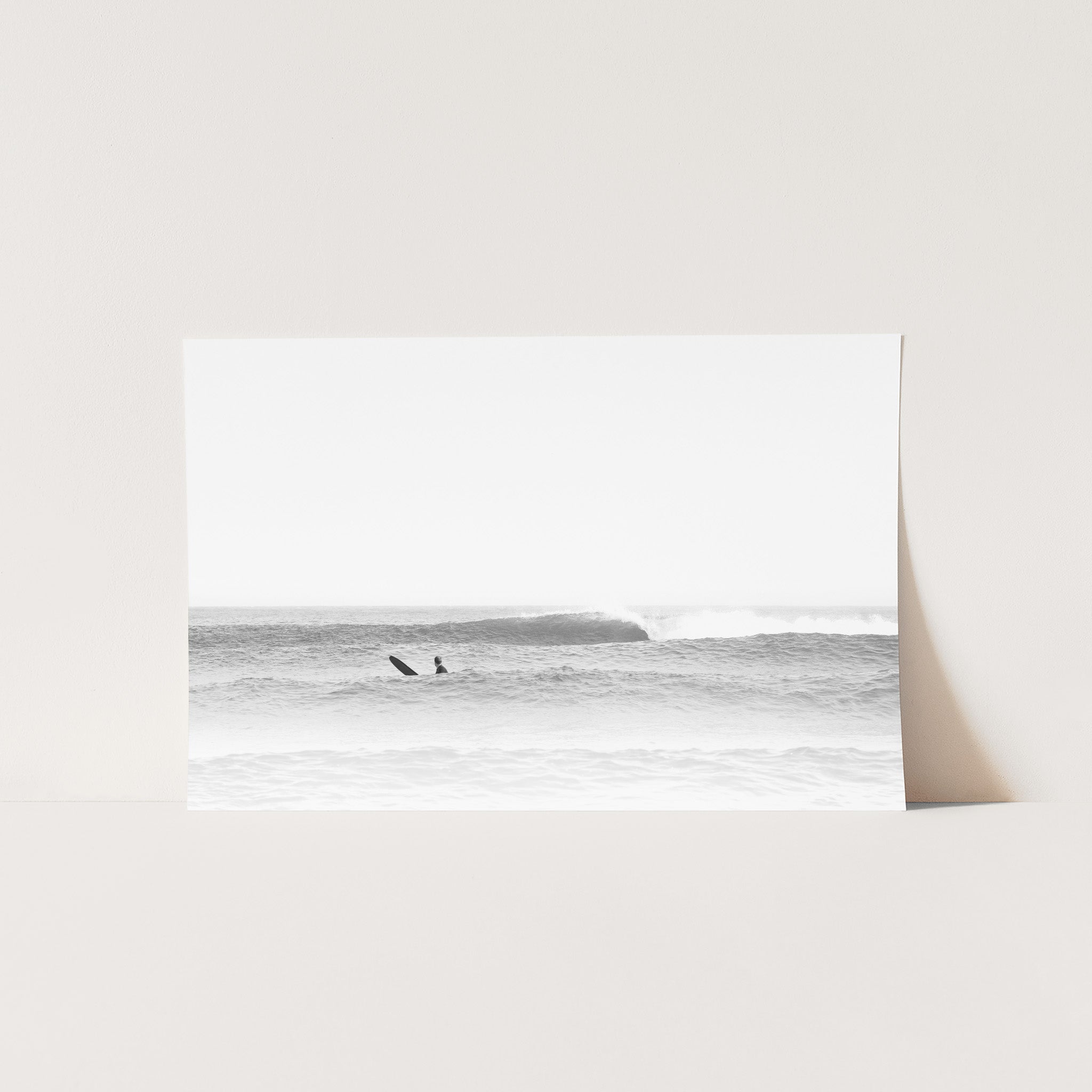 a black and white photo of two surfers in the ocean