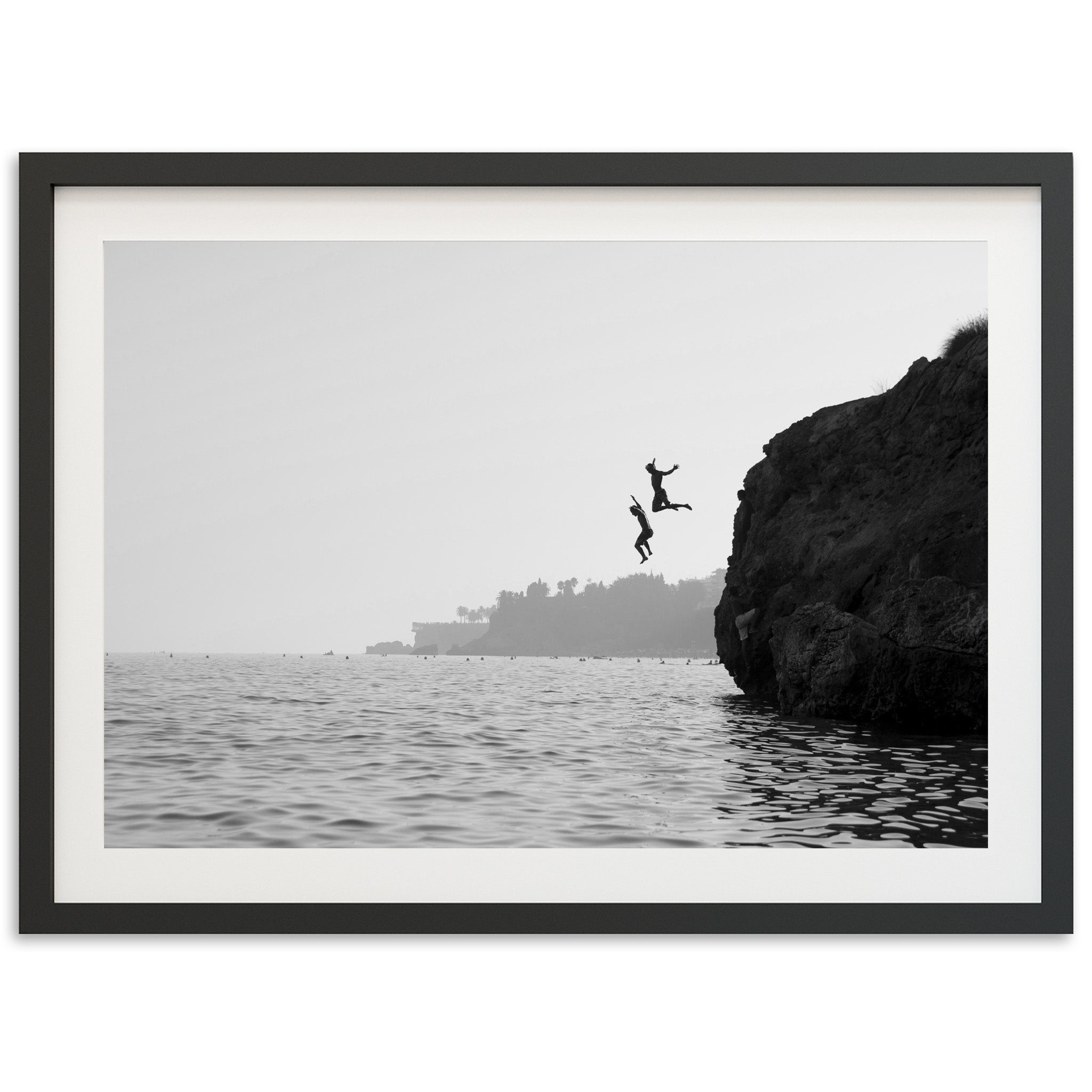 a black and white photo of a person jumping off a cliff into the ocean