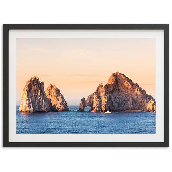 a framed photograph of three rock formations in the ocean