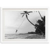 a black and white photo of a person hanging from a palm tree