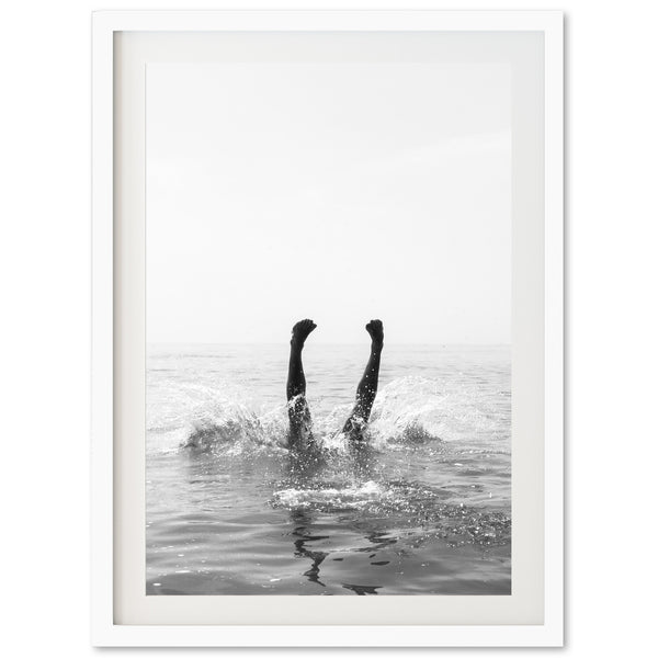 a black and white photo of two people swimming in the ocean