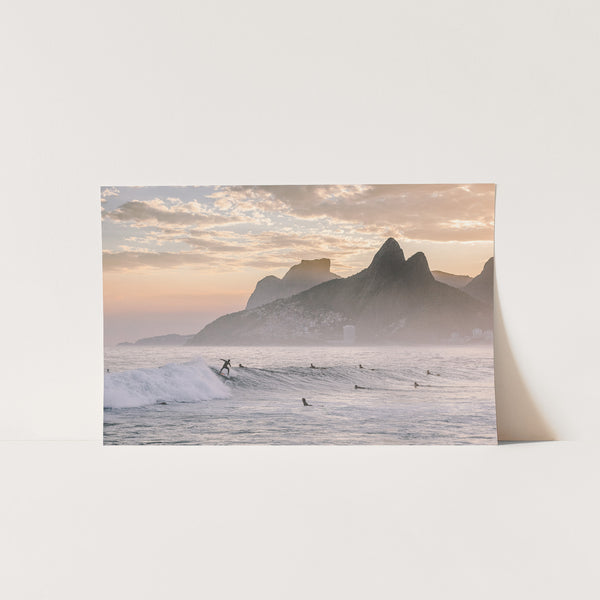 a picture of surfers in the ocean with mountains in the background