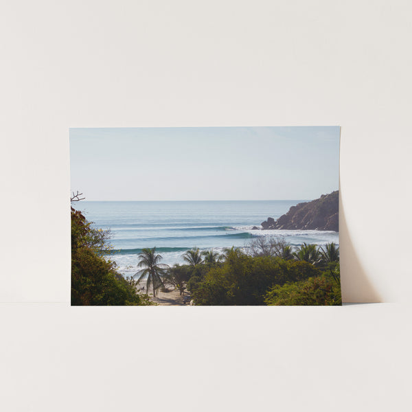 a picture of a beach with a surfboard in the foreground