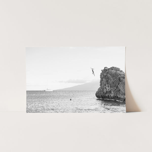 a black and white photo of a rock out in the ocean