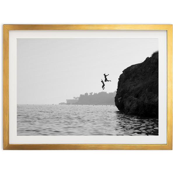 a black and white photo of a person jumping off a cliff into the ocean