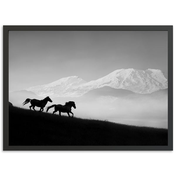 a black and white photo of two horses running