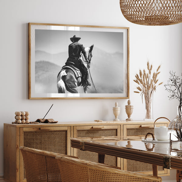 a black and white photo of a man riding a horse