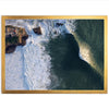 an aerial view of a wave crashing into the shore