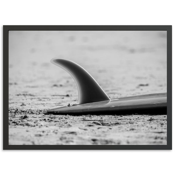 a black and white photo of a surfboard on the beach