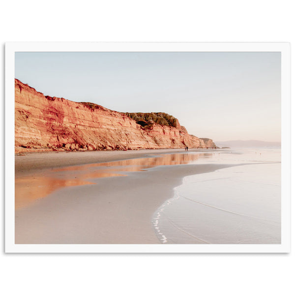 a person standing on a beach near a cliff