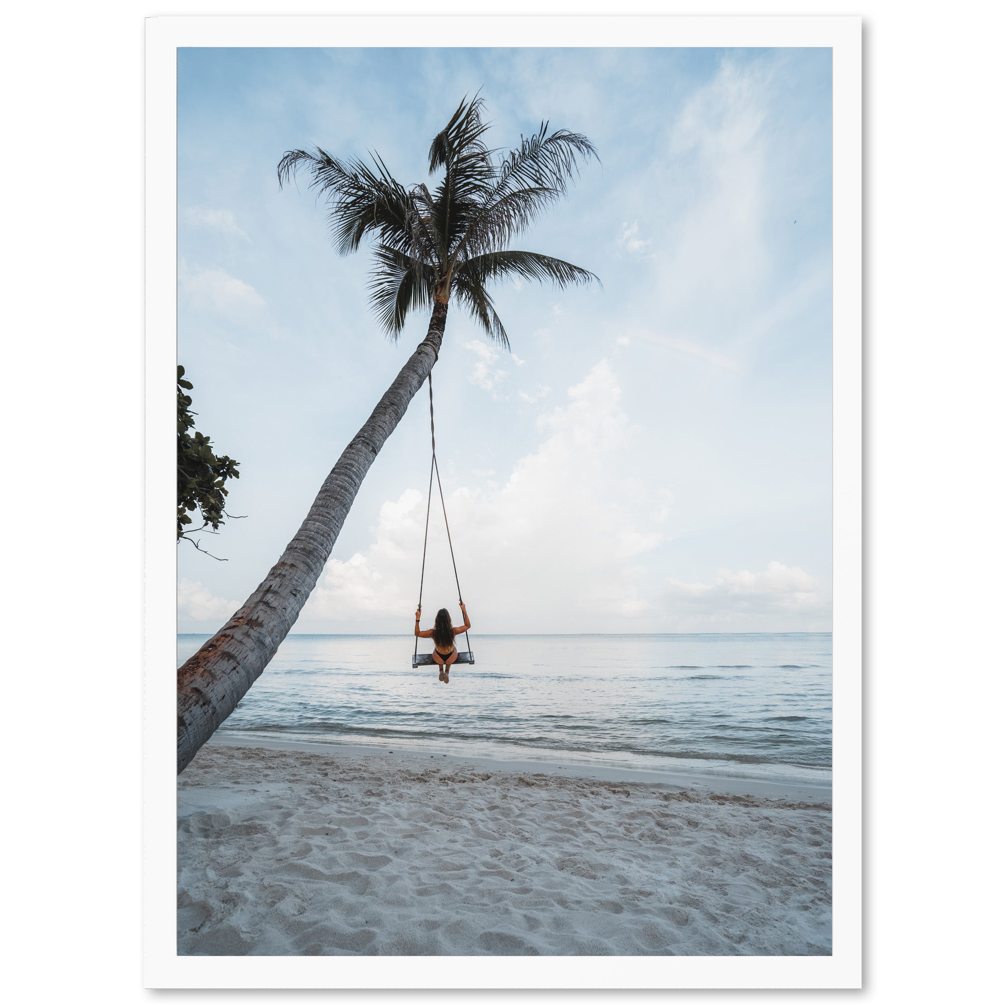 a woman sitting on a swing between two palm trees