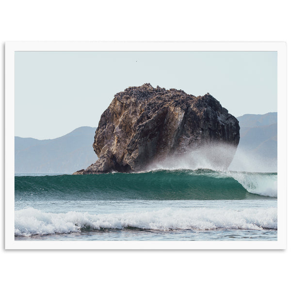 a large rock sitting on top of a wave in the ocean