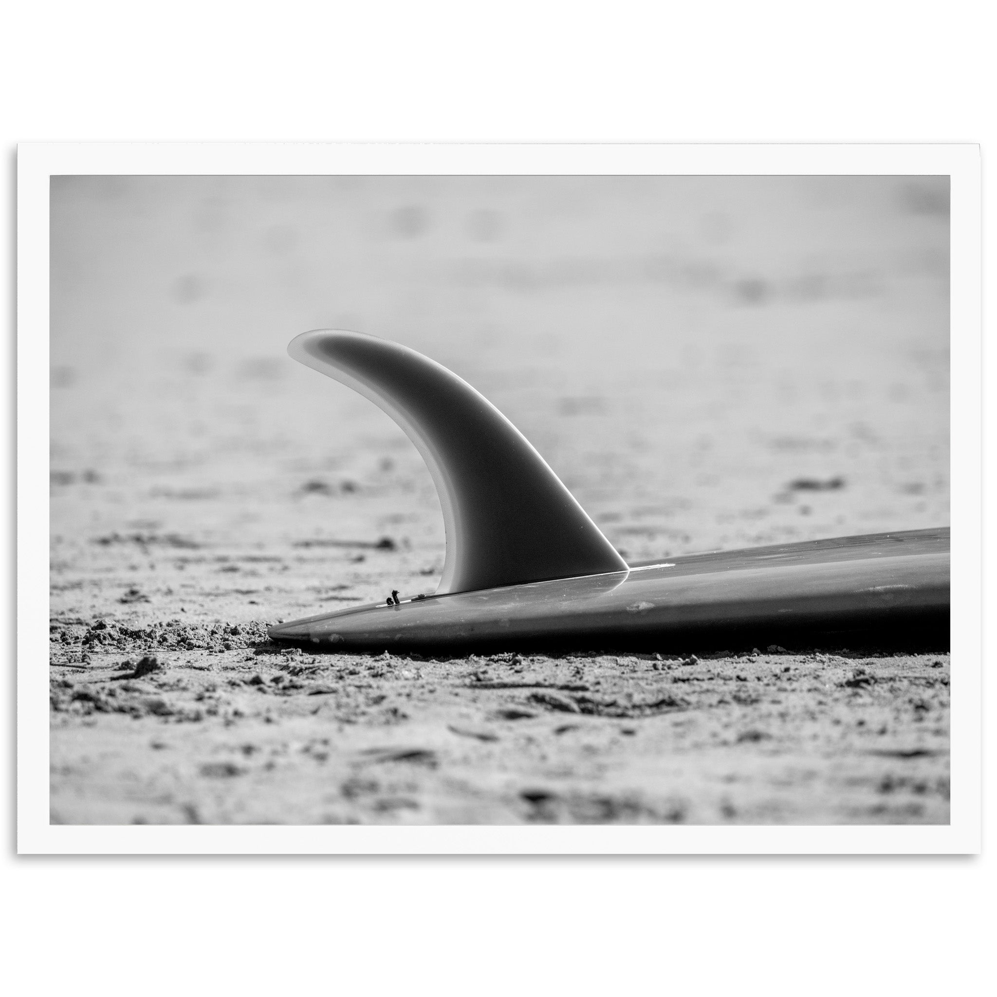 a black and white photo of a surfboard on the beach