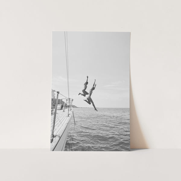 a black and white photo of a person jumping off a boat