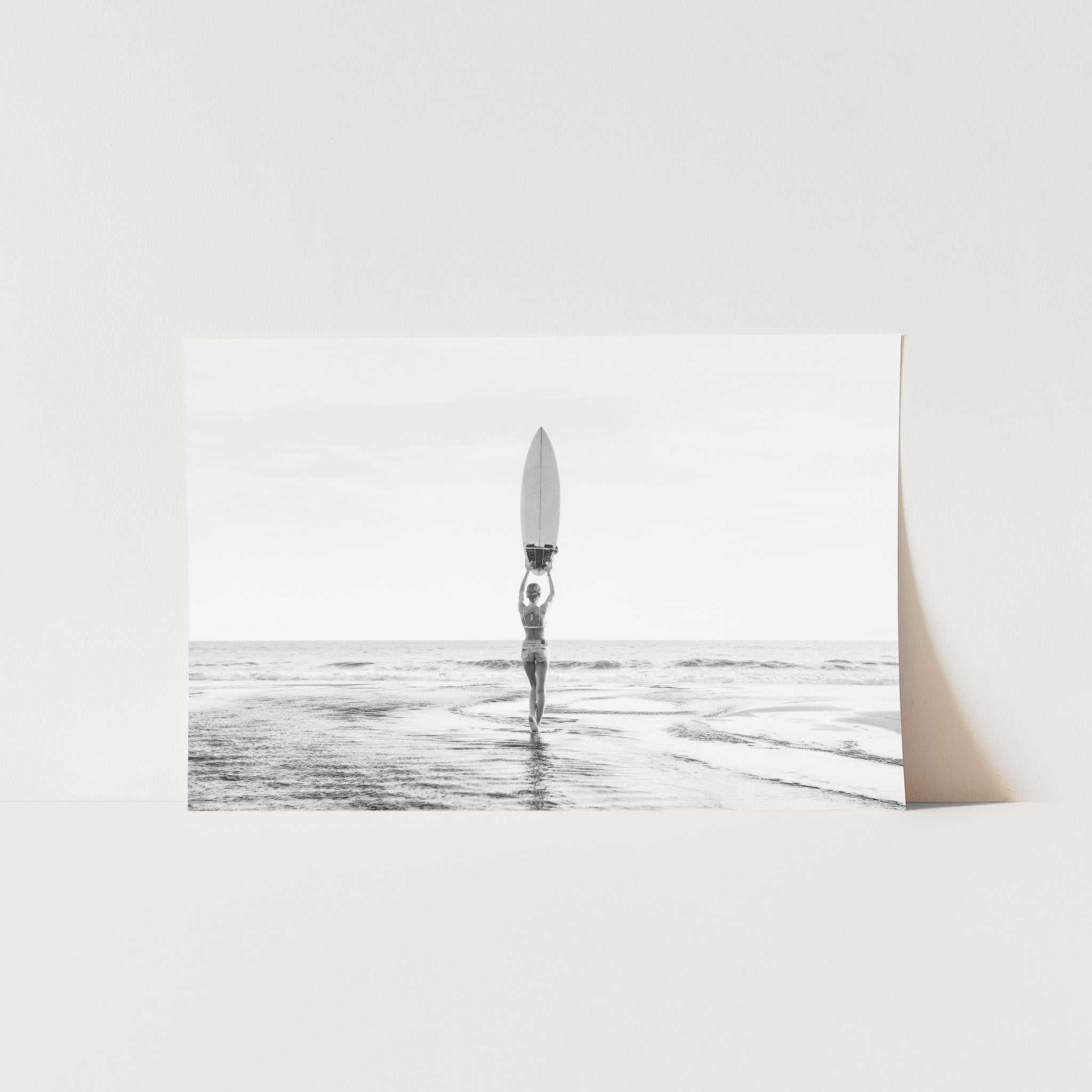 a black and white photo of a person holding a surfboard