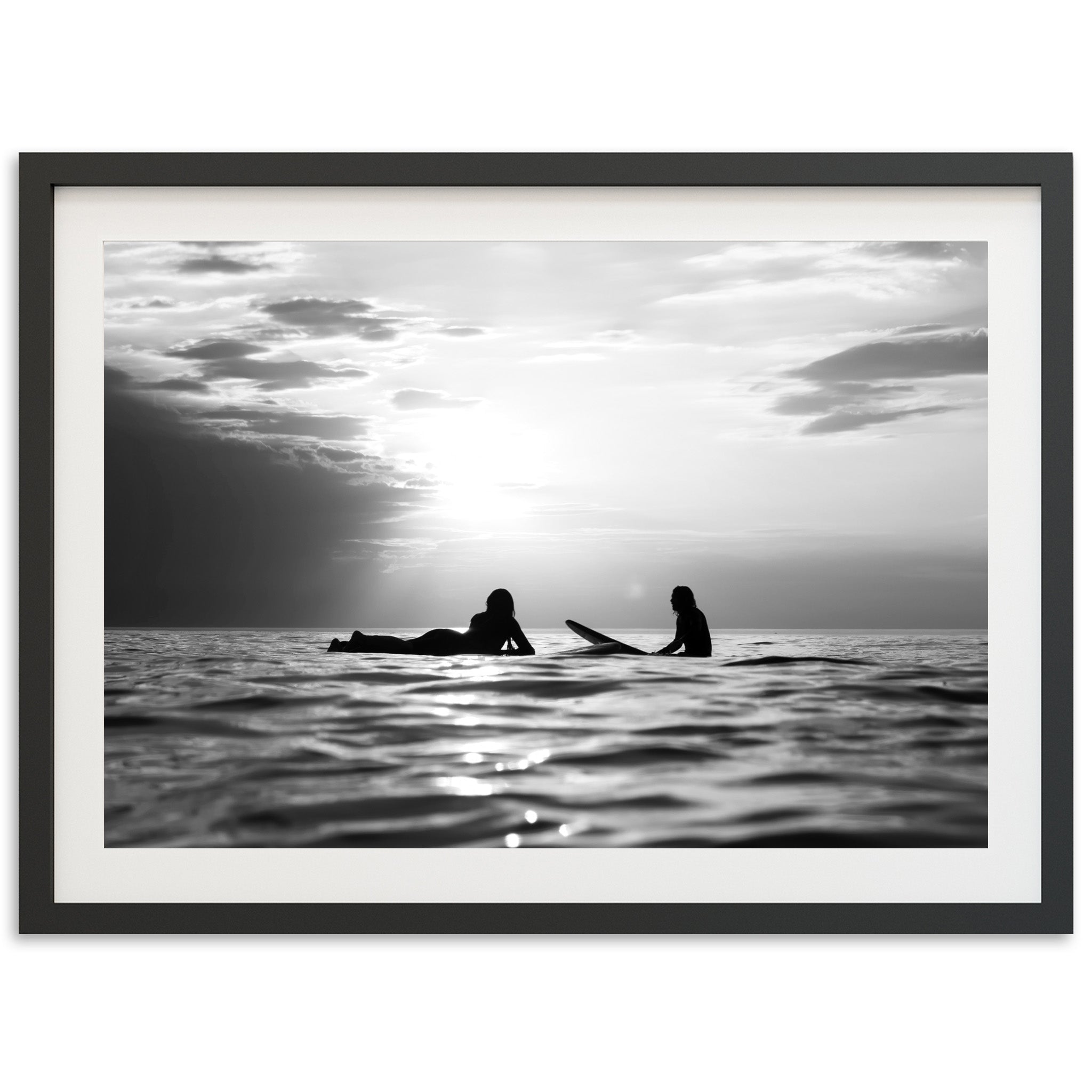 a black and white photo of two people in the ocean