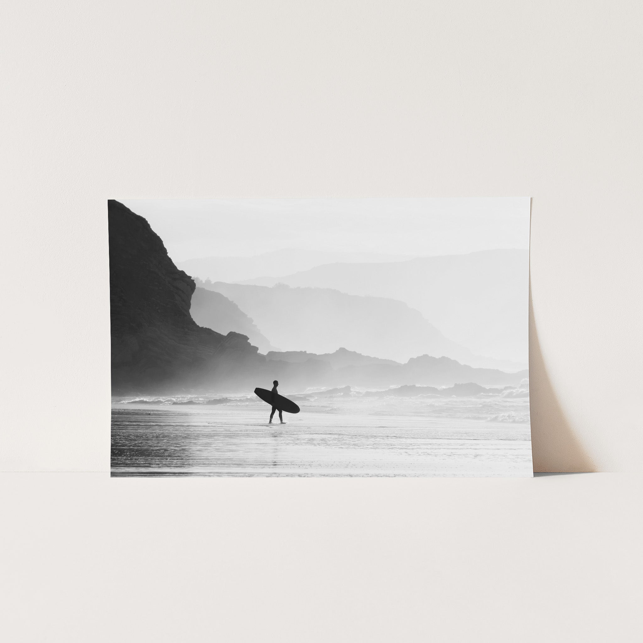 a black and white photo of a person carrying a surfboard