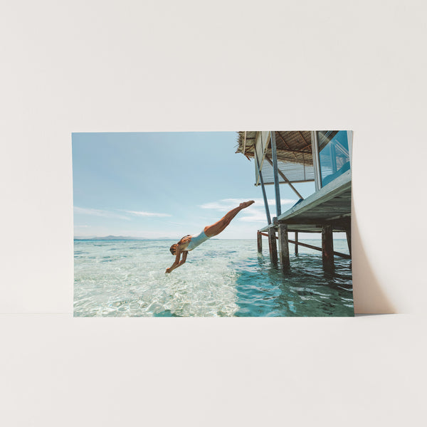 a man diving into the ocean from a dock