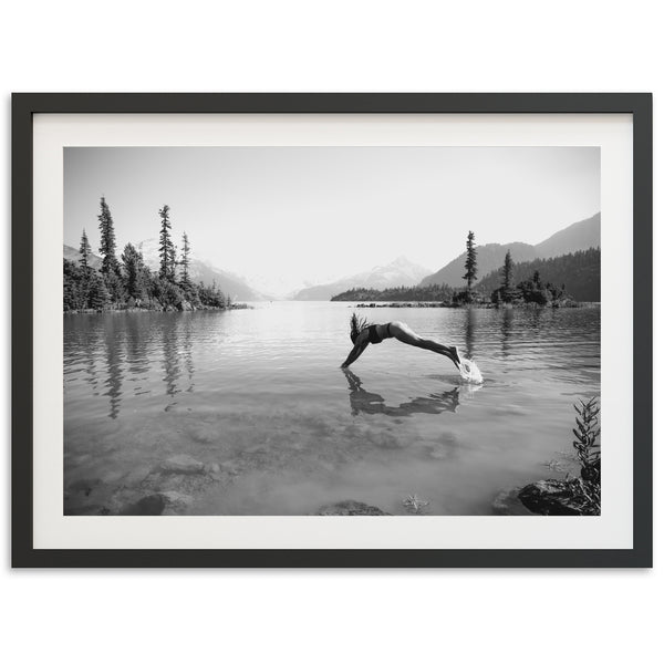 a black and white photo of a person diving into a lake