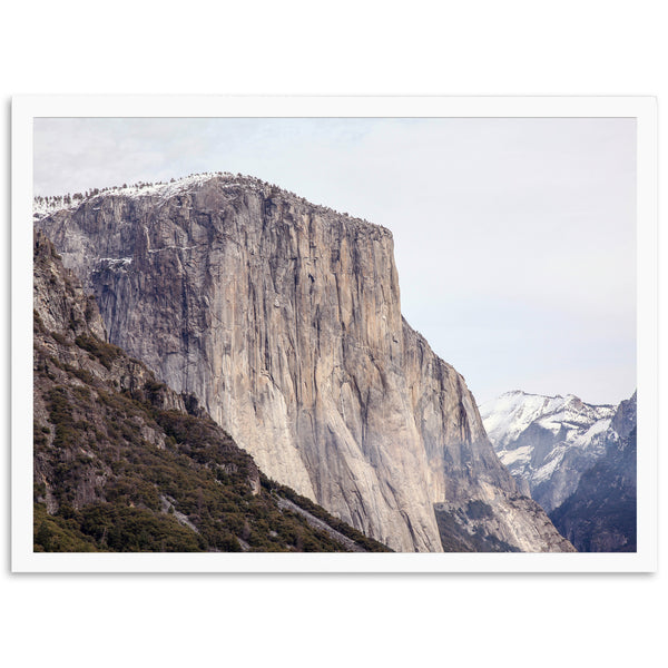 a mountain side with a snow covered mountain in the background