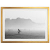 a black and white photo of a person carrying a surfboard