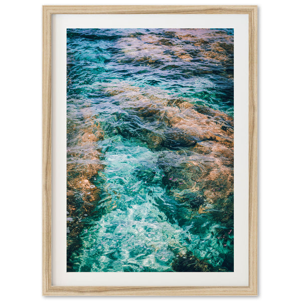 a framed photograph of water and rocks in the ocean